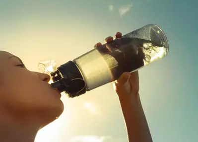 woman drinking water out of a bottle