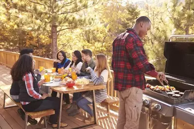 Friends enjoying a meal on the deck of a cabin.