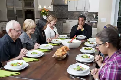 A large group of people saying grace before a meal.