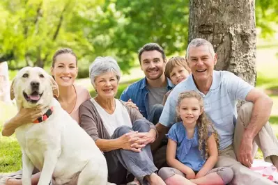 An extended family having a picnic with a happy dog.