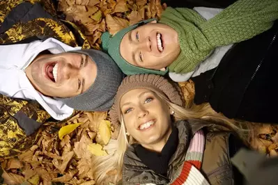 Young people relaxing in the leaves during the fall.