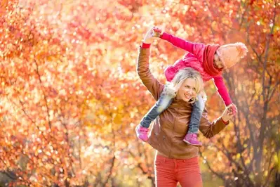 Mother and daughter playing outside during the fall.