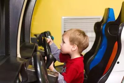 kid playing racing arcade game in cabin