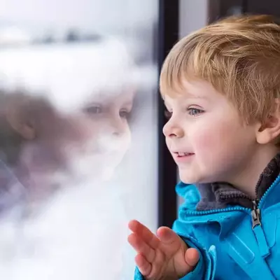 Young boy looking out the window at the snow