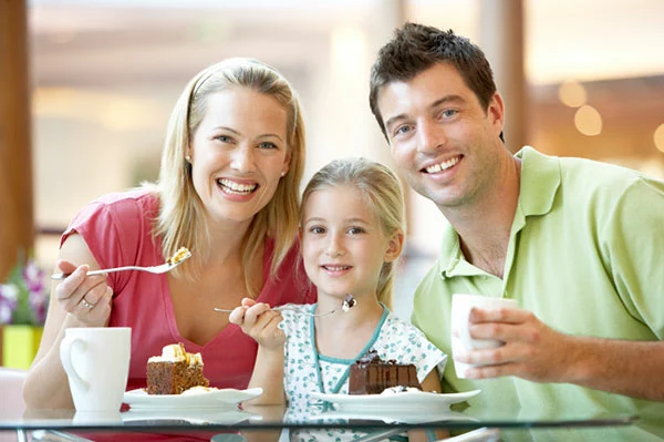 family eating dessert smiling at the camera